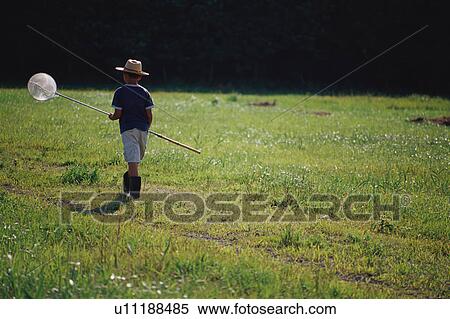 Stock Photography - Boy catching insects in field. Fotosearch