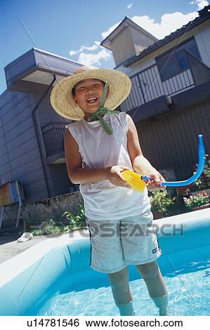 Stock Photograph - Boy standing in wading pool. Fotosearch