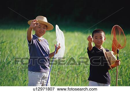 Boys catching insects in field View Large Photo Image Stock Photo - Boys catching insects in field. Fotosearch