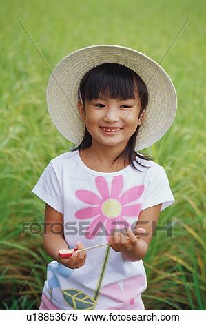 Girl standing in rice paddy holding toy View Large Photo Image Stock Photography - Girl standing in rice paddy holding toy. Fotosearch
