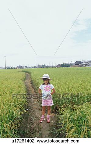 Stock Image - Girl standing in rice paddy. Fotosearch