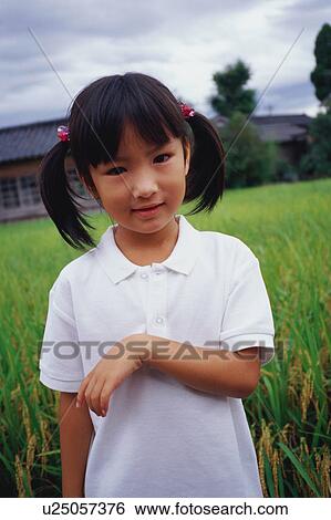 Stock Photograph - Girl standing in rice paddy. Fotosearch
