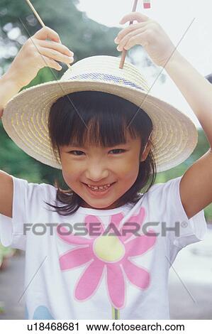 Stock Image - Girl wearing straw hat looking at camera. Fotosearch