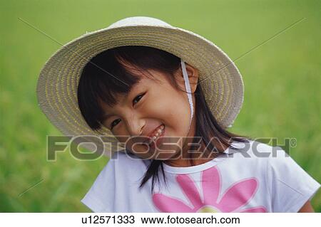 Stock Image - Girl wearing straw hat. Fotosearch