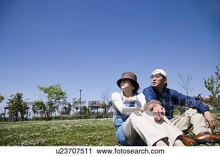 Stock Image - Mature couple sitting on ground. Fotosearch