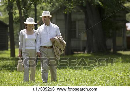 Stock Image - Mature couple walking in park. Fotosearch