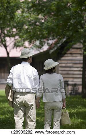 Stock Image - Mature couple walking in park. Fotosearch