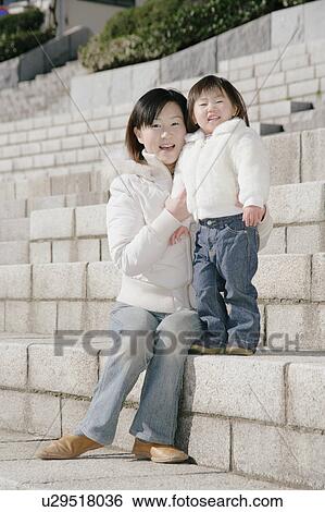 Stock Photograph - Portrait of mother sitting with her daughter. Fotosearch