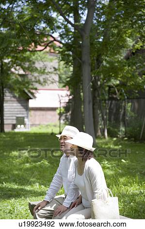 Stock Image - Mature couple sitting on bench. Fotosearch