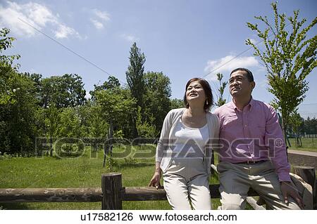 Stock Photograph - Mature couple sitting on fence. Fotosearch