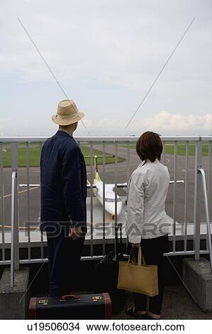 Picture - Senior couple looking at airplane at airport. Fotosearch