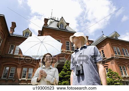 Stock Image - Senior couple standing in front of building. Fotosearch