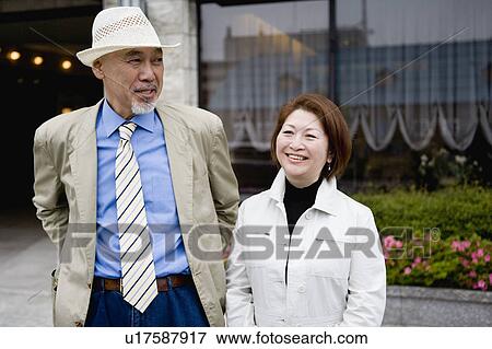 Stock Photo - Senior couple standing in front of building. Fotosearch