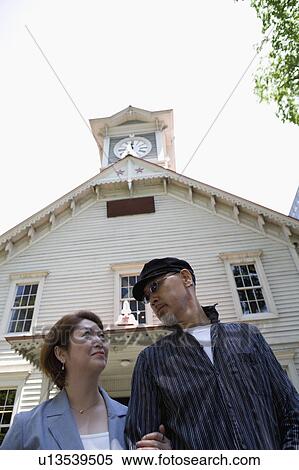 Stock Photography - Senior couple standing in front of clock tower. Fotosearch