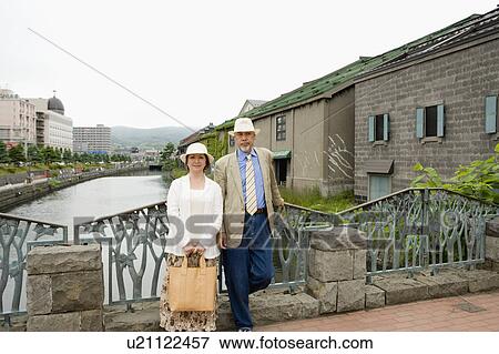 Stock Photo - Senior couple standing on bridge. Fotosearch
