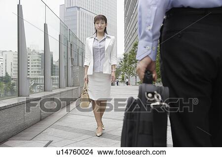 Picture - A formally dressed woman walking on the bridge with a bag. Fotosearch