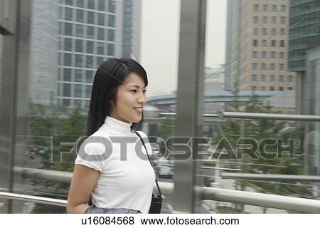 Stock Photo - A side view of a woman seen smiling against the railing. Fotosearch