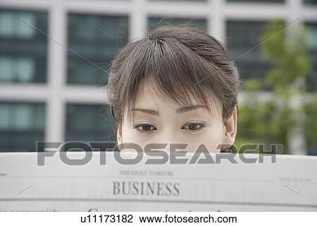 Stock Image - A woman attentively reading the newspaper. Fotosearch