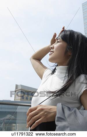 Stock Image - A woman hides her eye as she gets basked in sunlight. Fotosearch