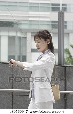 Stock Photo - A woman looking at her watch as she is on her way. Fotosearch