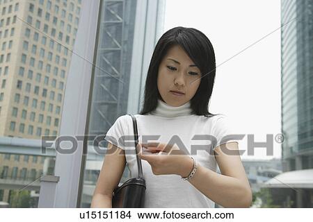 A woman looks over her watch near a commercial area View Large Photo Image Picture - A woman looks over her watch near a commercial area. Fotosearch