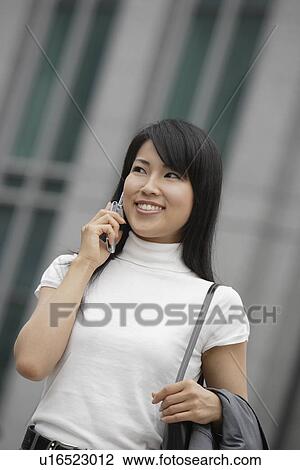 A woman smiling as she converses on the mobile phone View Large Photo Image Stock Image - A woman smiling as she converses on the mobile phone. Fotosearch