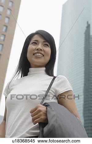 Stock Photography - A woman smiling with skyscrapers at the background. Fotosearch