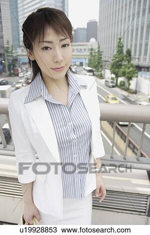 Stock Image - A woman standing against the railing as she smiles at the camera. Fotosearch