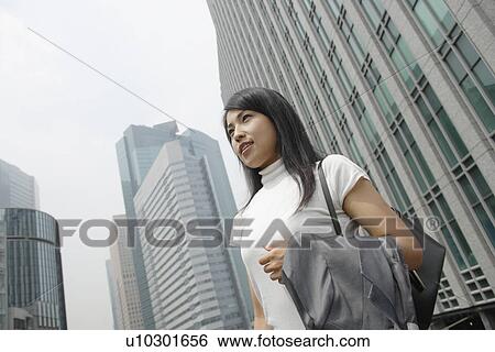 Stock Photograph - A woman standing amidst a commercial area. Fotosearch