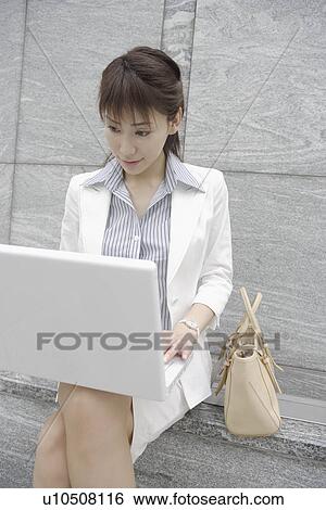 A woman working on her laptop with a bag beside her View Large Photo Image Stock Photograph - A woman working on her laptop with a bag beside her. Fotosearch