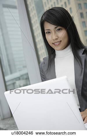 A woman working over her laptop in a commercial area View Large Photo Image Stock Photograph - A woman working over her laptop in a commercial area. Fotosearch