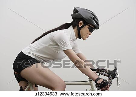 Stock Image - Close-up of a young woman bicycling. Fotosearch