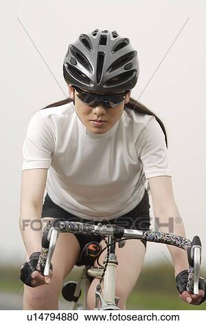 Stock Image - Close-up of a young woman bicycling. Fotosearch