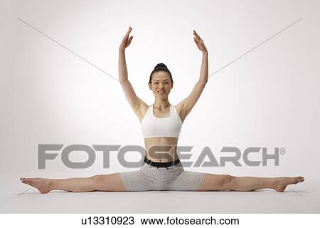 Stock Image - View of a young woman exercising on the floor. Fotosearch