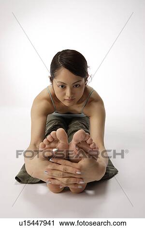 Stock Image - View of a young woman exercising on the floor. Fotosearch