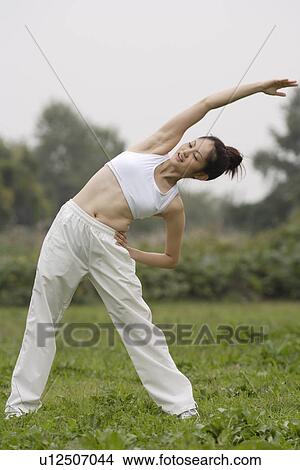 Picture - View of a young woman exercising outdoors. Fotosearch