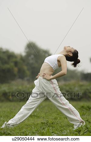 Picture - View of a young woman exercising outdoors. Fotosearch