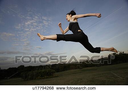 Stock Photo - View of a young woman jumping in the air. Fotosearch