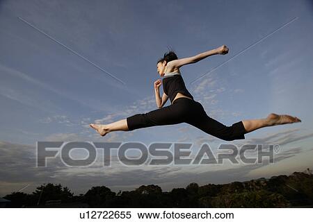 Stock Photography - View of a young woman jumping in the air. Fotosearch