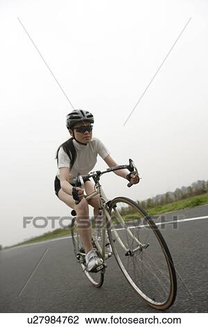 View of a young woman riding a racing bike View Large Photo Image Stock Image - View of a young woman riding a racing bike. Fotosearch