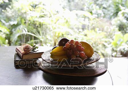 Stock Photography - Close-up of fruit and books kept on a table. Fotosearch