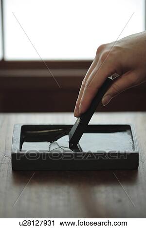 Stock Image - View of a person mixing paint in a box. Fotosearch