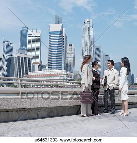 Stock Image - Businessman talking to three businesswomen. Fotosearch