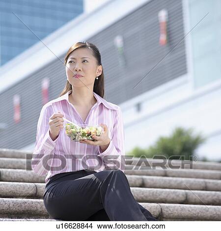 Picture - Close-up of a businesswoman holding a bowl of salad. Fotosearch