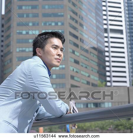 Picture - Low angle view of a businessman leaning over a railing. Fotosearch