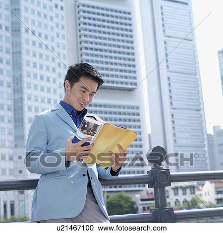 Stock Image - Low angle view of a businessman reading a magazine. Fotosearch