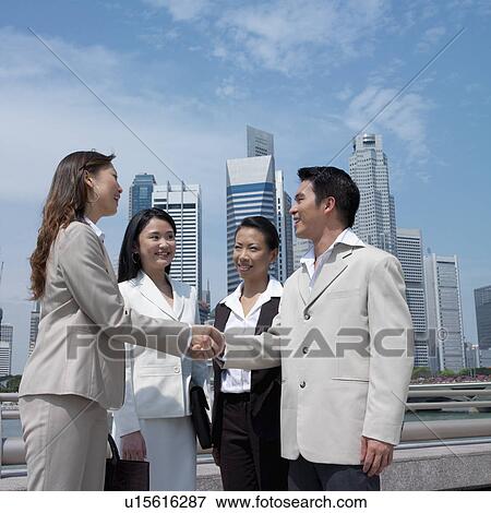 Stock Photo - Low angle view of a businessman shaking hands with a businesswoman. Fotosearch