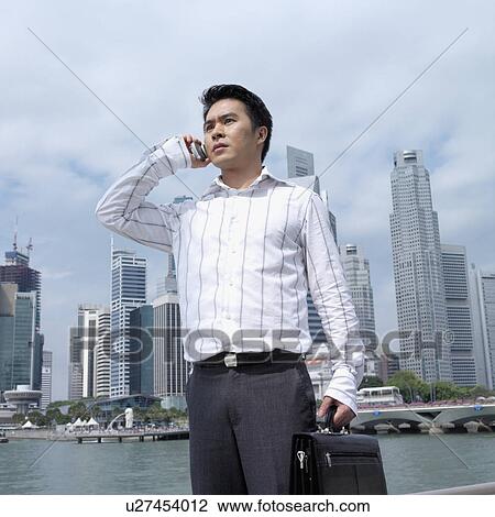 Stock Image - Low angle view of a businessman talking on a mobile phone. Fotosearch
