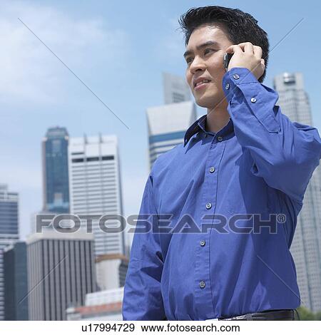 Low angle view of a businessman talking on a mobile phone View Large Photo Image Stock Photo - Low angle view of a businessman talking on a mobile phone. Fotosearch