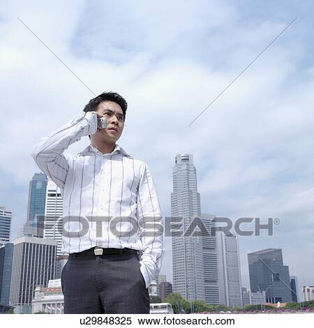 Stock Photography - Low angle view of a businessman talking on a mobile phone. Fotosearch